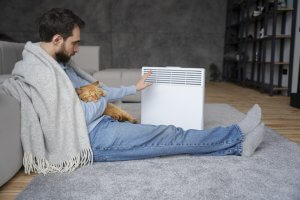man sitting with pet cat in front of infrared heaters